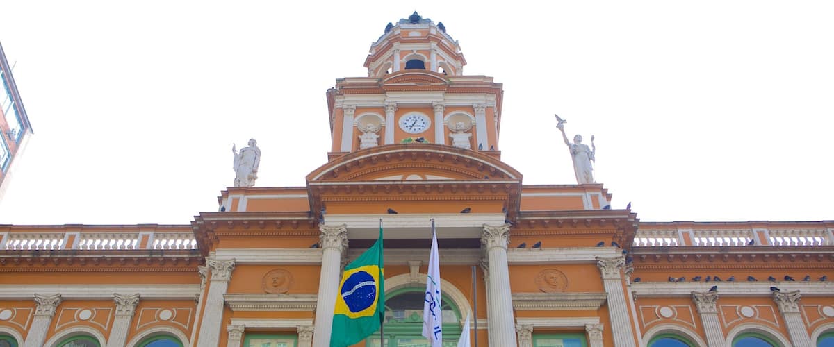 A grand building with a clock tower, statues, and flags.
