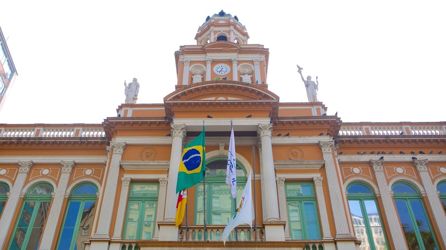 A grand building with a clock tower, statues, and flags.