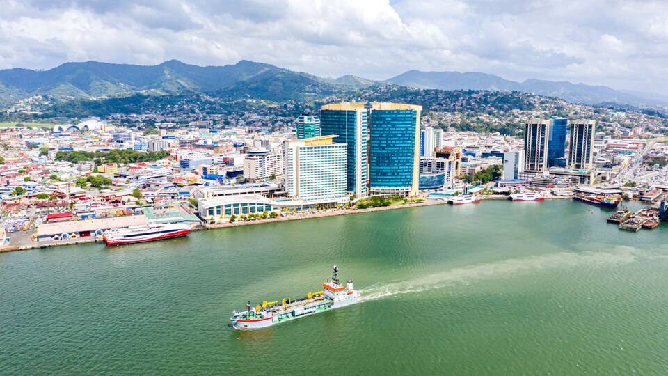 Aerial view of city of Port of Spain, the capital city of Trinidad and Tobago. Skyscrapers of the downtown and a busy sea port with commercial docks and passenger catamarans