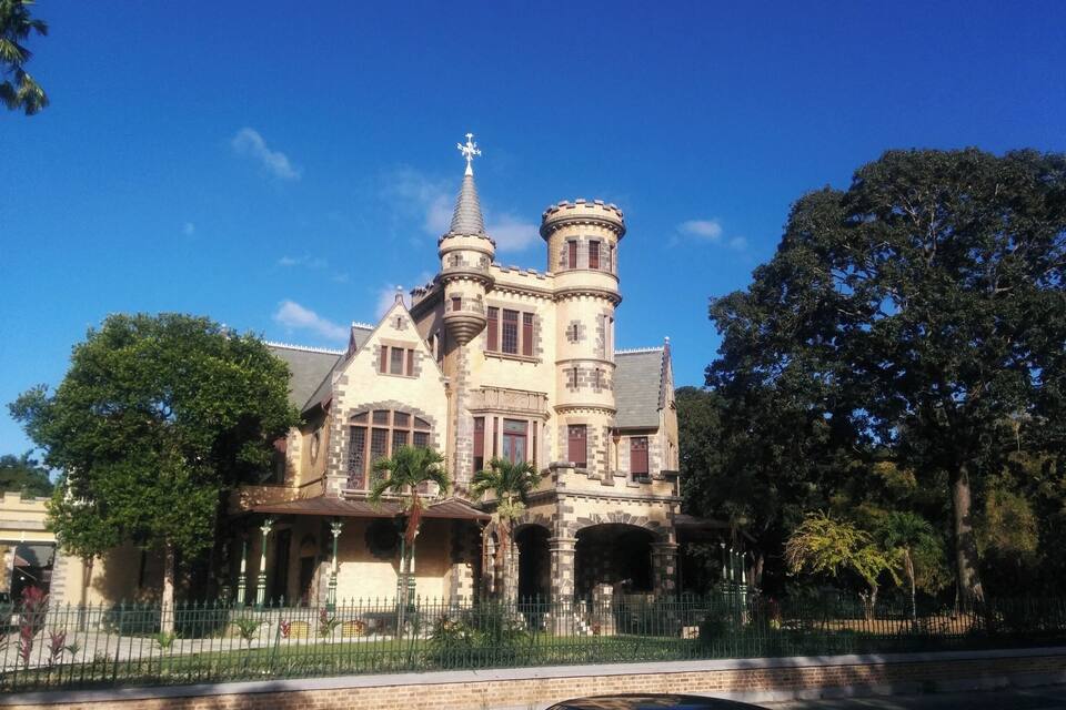 Un grand bâtiment historique doté d’une tour et de tourelles, entouré d’arbres et d’une clôture.