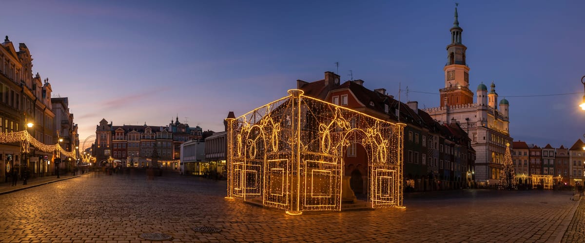 A cobblestone square with a decorated gazebo and historic buildings in the background.