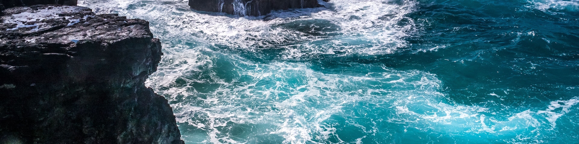 Um litoral rochoso com ondas quebrando nas rochas.