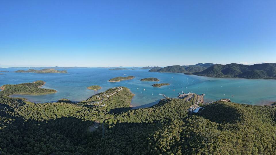 An aerial view of a coastal area with multiple islands surrounded by clear blue waters and dense green forests.