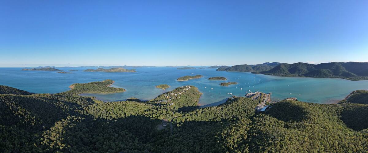 An aerial view of a coastal area with multiple islands surrounded by clear blue waters and dense green forests.