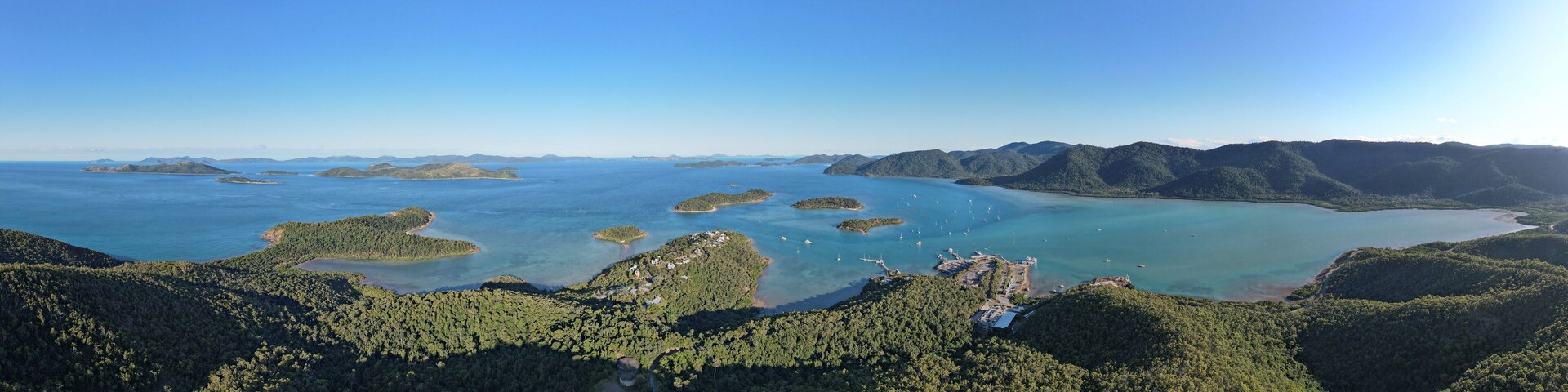 An aerial view of a coastal area with multiple islands surrounded by clear blue waters and dense green forests.