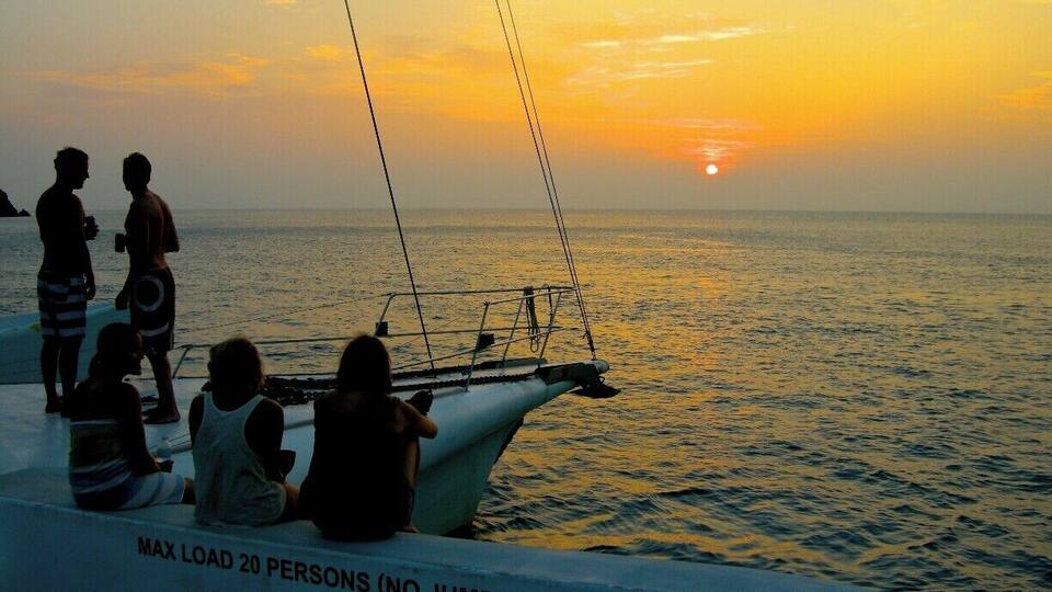 A boat with people at sunset.