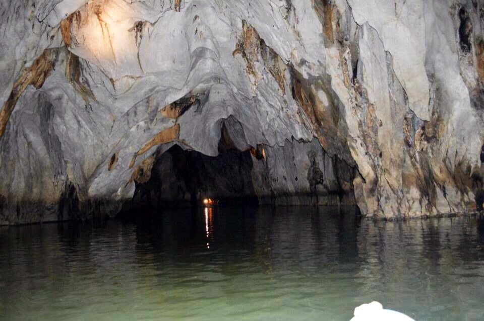 Una cueva con estalactitas y estalagmitas, iluminada por una fuente de luz.