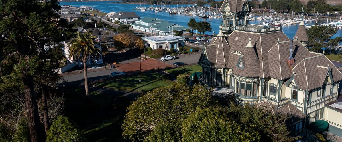 A coastal town with a prominent church steeple, marina, and surrounding greenery.