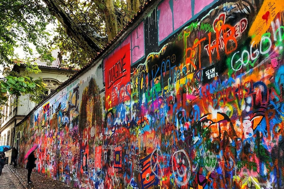 A colorful graffiti-covered wall with trees overhead.