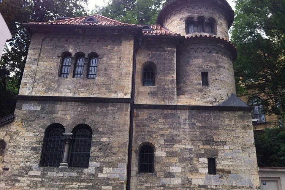 Ein historisches Steinhaus mit einem Türmchen und Rundbogenfenstern.