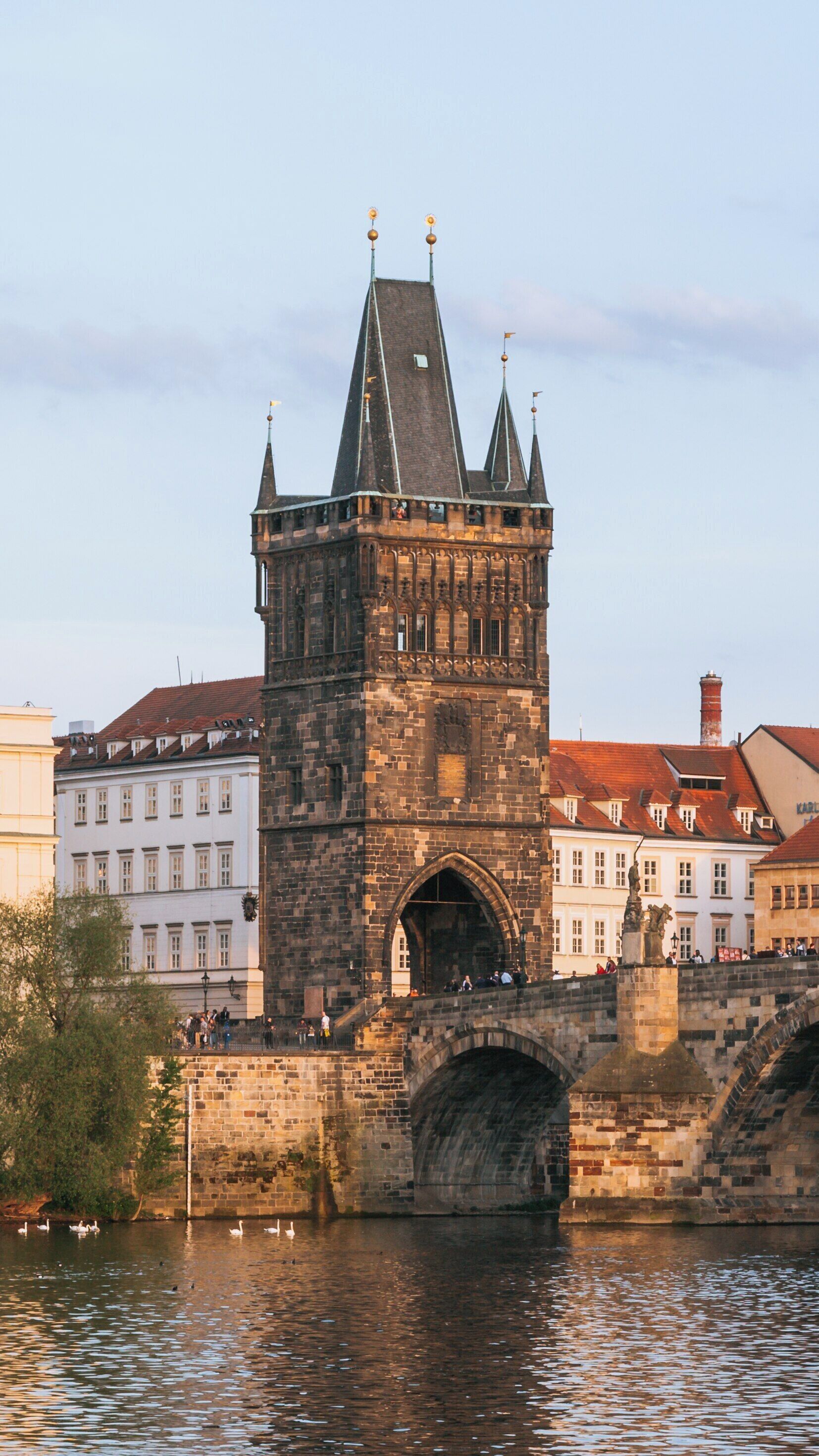 Exploring Old Town Bridge Tower at sunset in Prague with reflections in the river