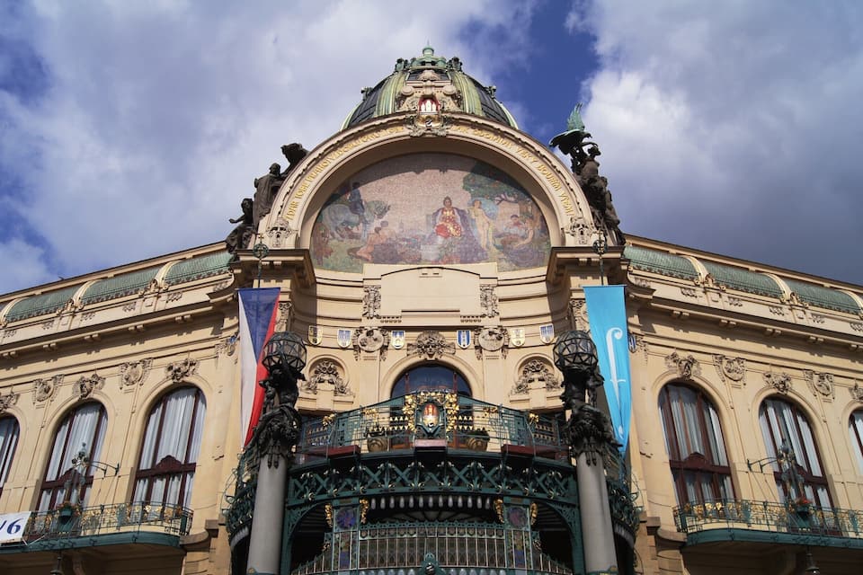 A grand building with ornate architecture, a large central arch, and a detailed mosaic above the entrance.