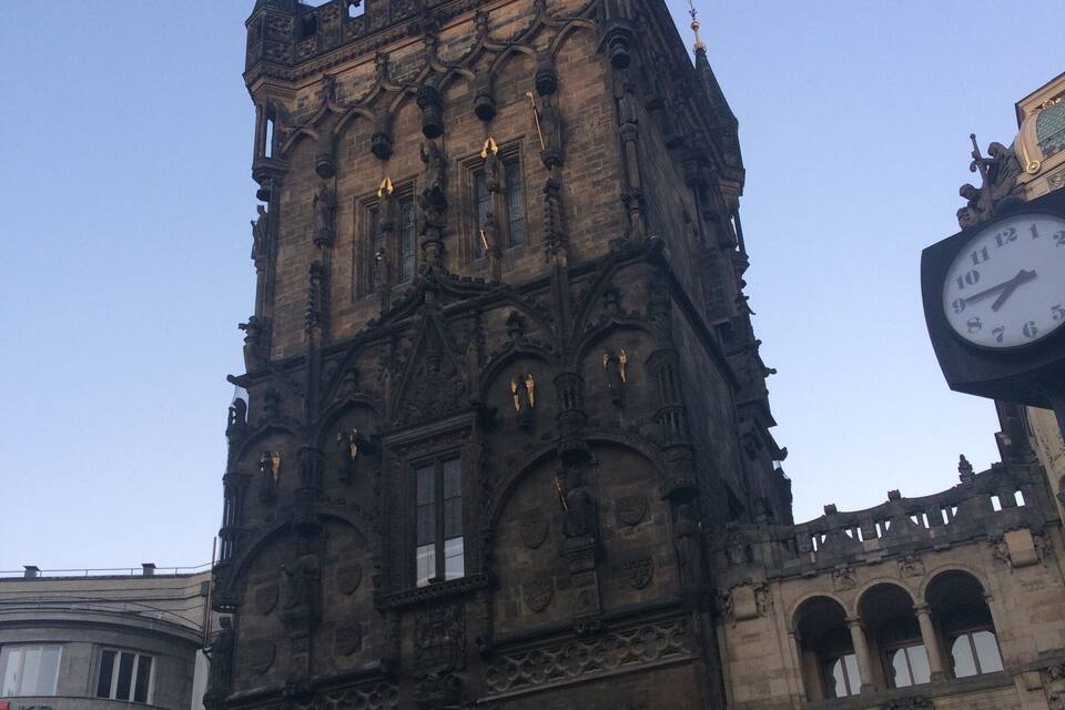 Uma torre histórica com arquitetura elaborada e um grande relógio.