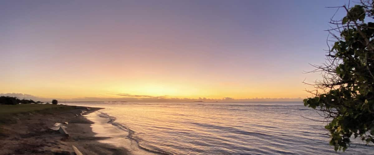 A beach with sand and water at sunset.