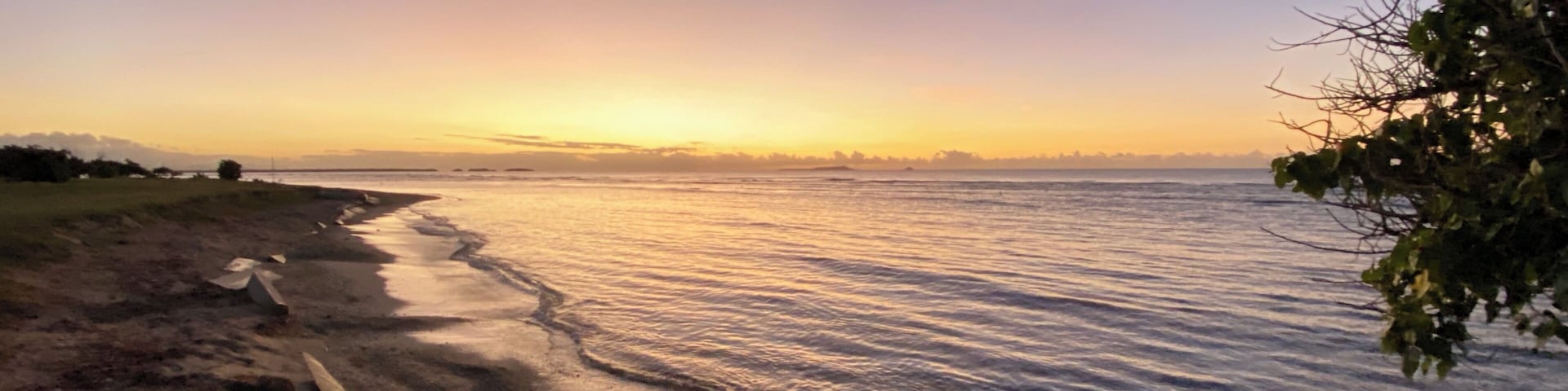 A beach with sand and water at sunset.
