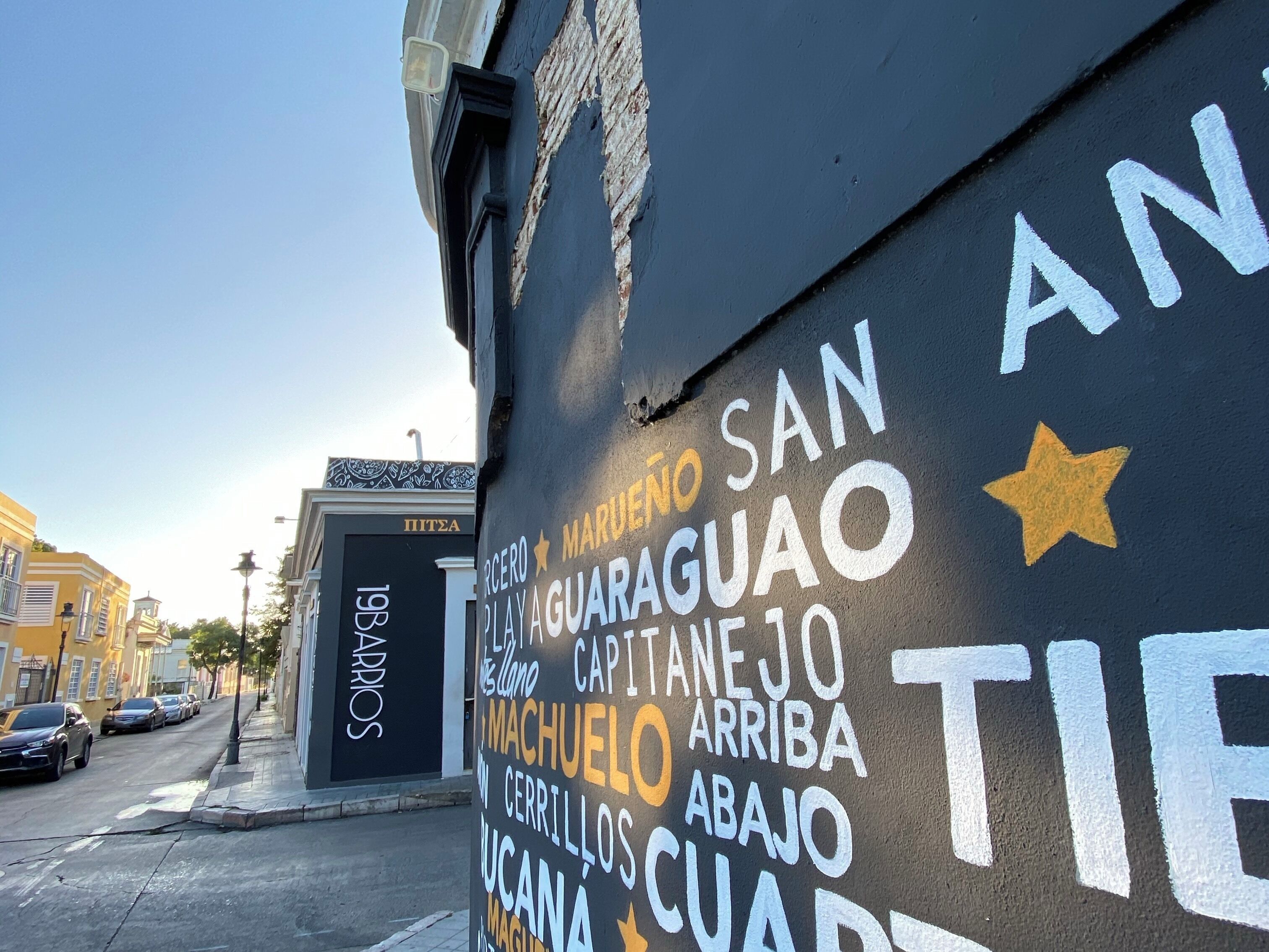 A street with a mural featuring names of places and directions.