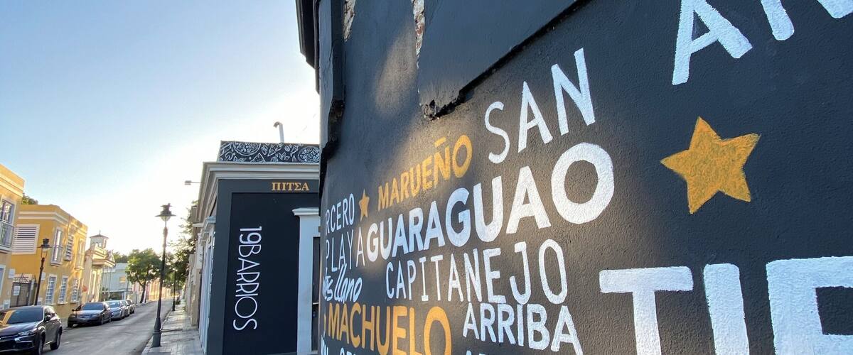 A street with a mural featuring names of places and directions.