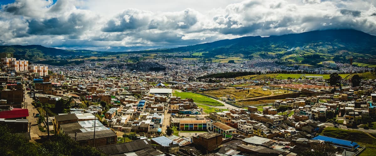 A cityscape with a mountain in the background and a cloudy sky.