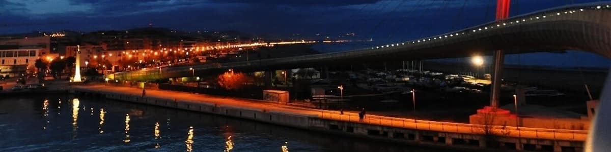 Eine Brücke im Abenddämmerung, das Wasser spiegelt Lichter wider.