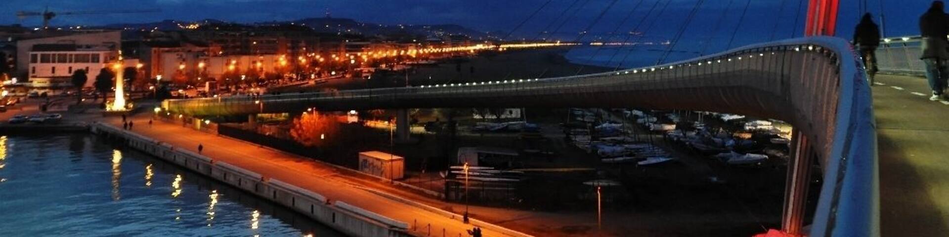 A cable-stayed bridge at dusk with city lights reflecting on the water.