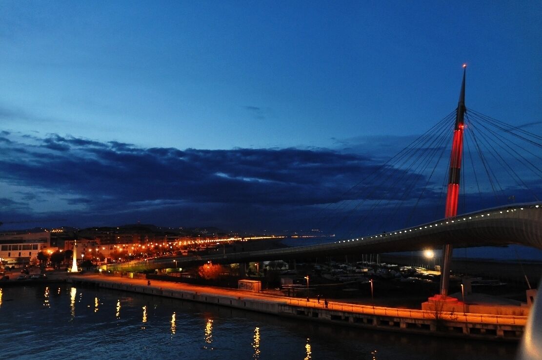 A cable-stayed bridge at dusk with city lights reflecting on the water.