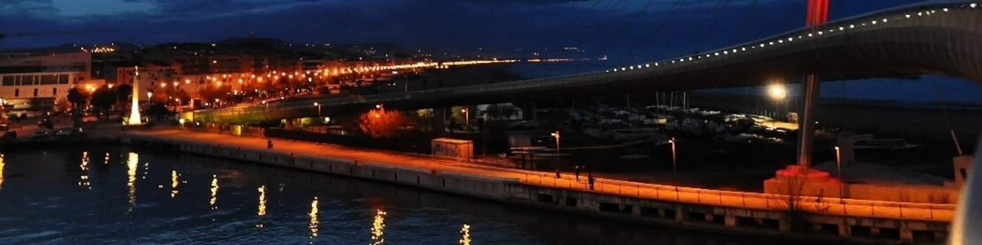 A cable-stayed bridge at dusk with city lights reflecting on the water.