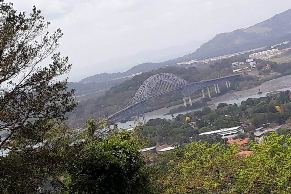Eine Brücke über einem Fluss, im Hintergrund Hügel.