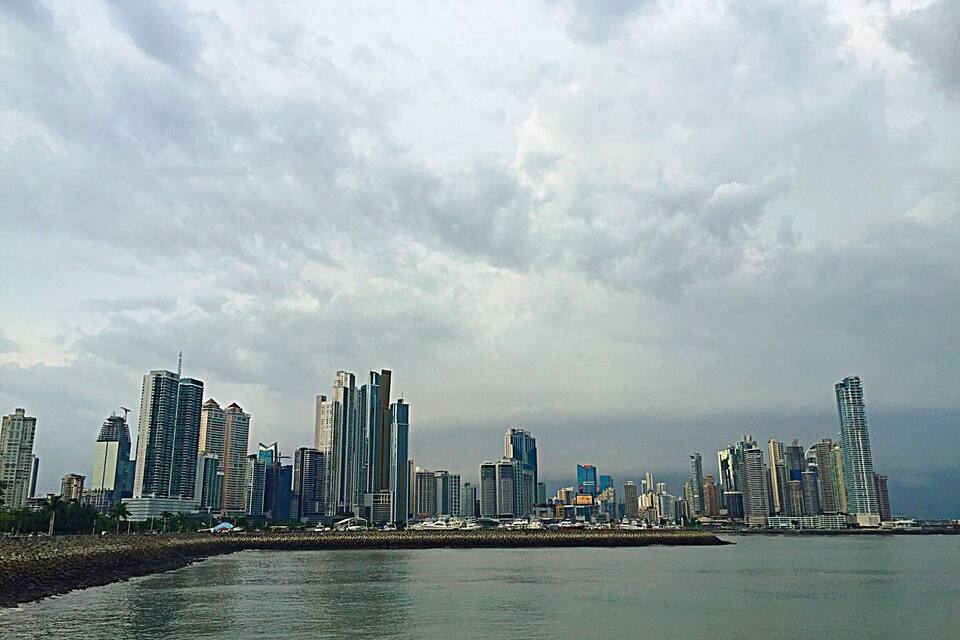 A coastal city skyline with modern skyscrapers and a rocky shoreline.