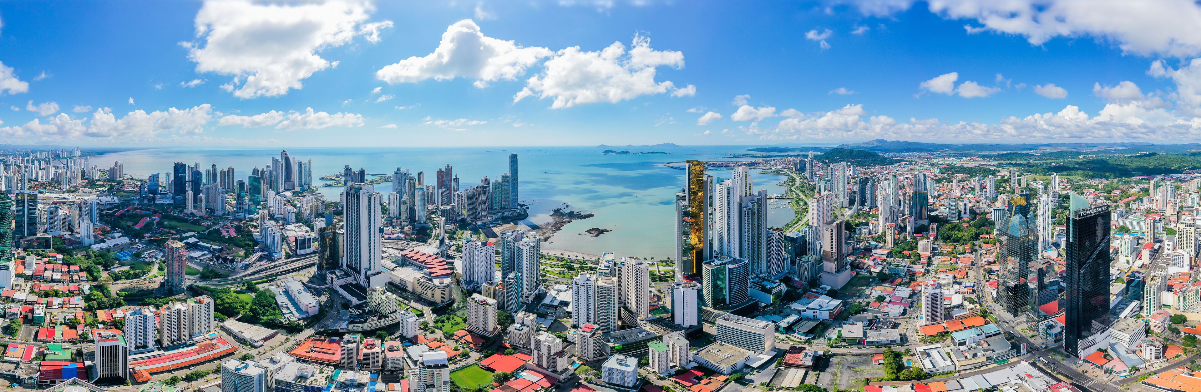 A coastal cityscape with high-rise buildings, a marina, and a clear blue sky.