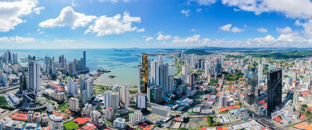 A coastal cityscape with high-rise buildings, a marina, and a clear blue sky.