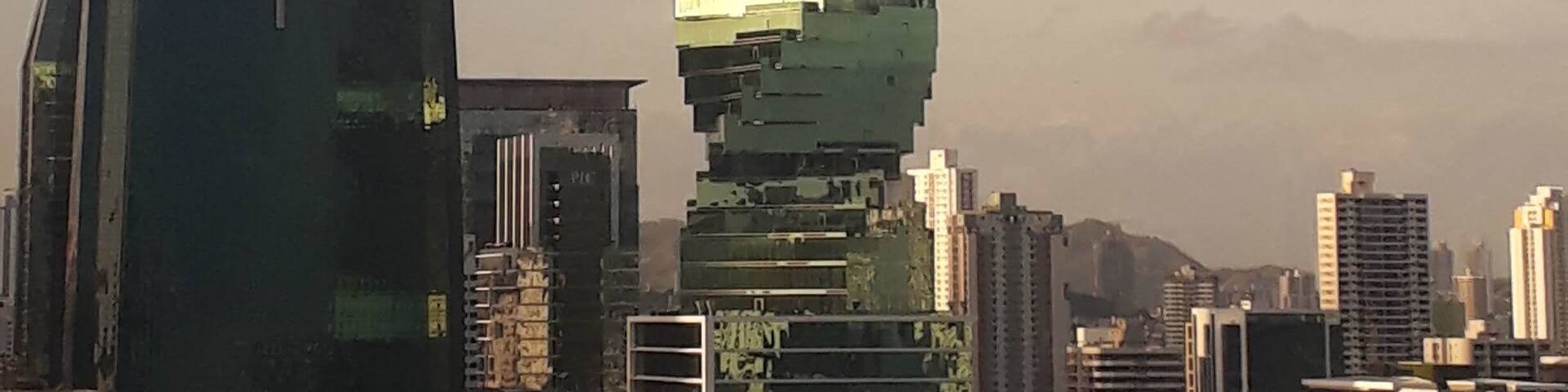 A modern, spiraling skyscraper with a unique design, surrounded by other buildings in an urban setting.