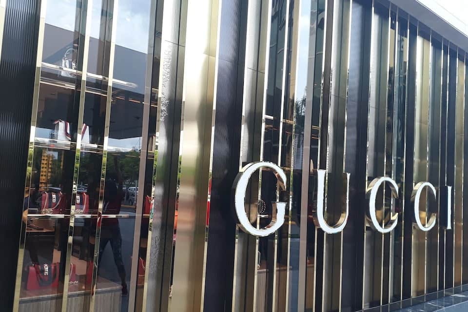 En moderne bygning med en facade af lodrette, reflekterende paneler, hvor teksten "GUCCI" er tydeligt synlig.