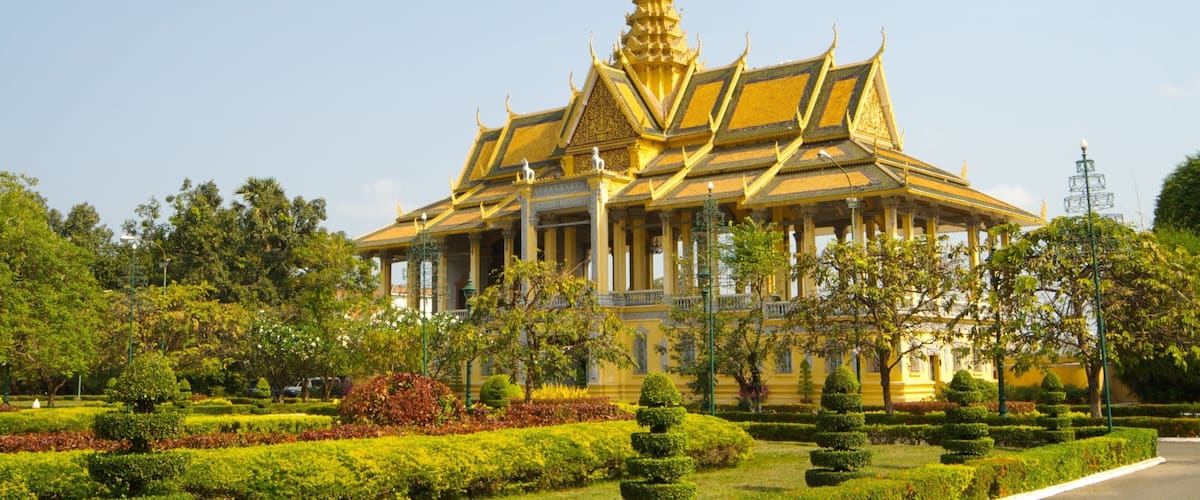 A golden temple with intricate architecture surrounded by lush greenery.
