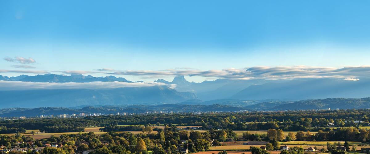 A mountainous landscape with a town in the foreground and a prominent peak in the background.