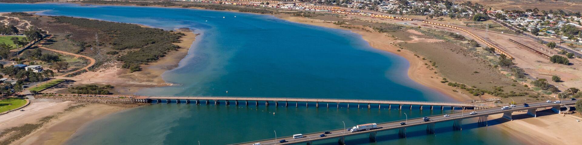 A coastal bridge, a river, and distant mountains.