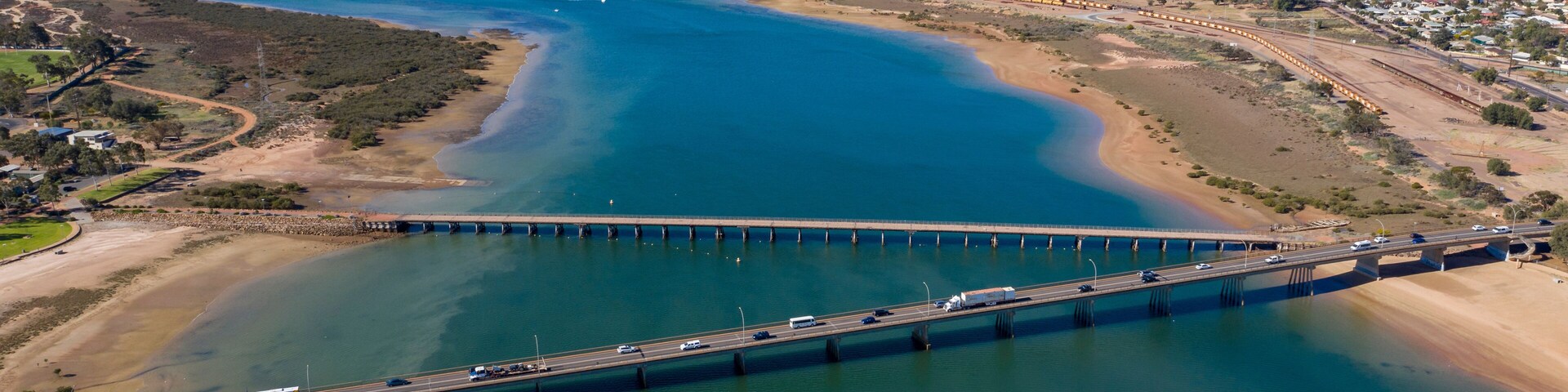Uma ponte costeira, um rio e montanhas ao longe.