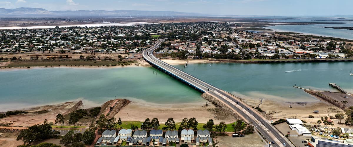 A coastal town with a bridge over a river, surrounded by residential areas and a beach.