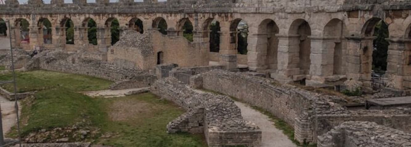 The most famous and important monument, the starting and ending point of every sightseeing tour is the Amphitheater, popularly called the Arena of Pula, which was once the site of gladiator fights. It was built in the 1st century AD during the reign of Emperor Vespasian, at the same time as the magnificent Colosseum in Rome.
The ground plan is elliptical, the longer axis measuring about 130 m and the shorter one about 100 m. Gladiator fights took place in the central flat area called the arena, while the spectators could sit on the stone tiers or stand in the gallery. It is believed that the Amphitheater could seat about 20,000 spectators. Local limestone was used for its construction. In the Middle Ages it was the site of knights tournaments and fairs.