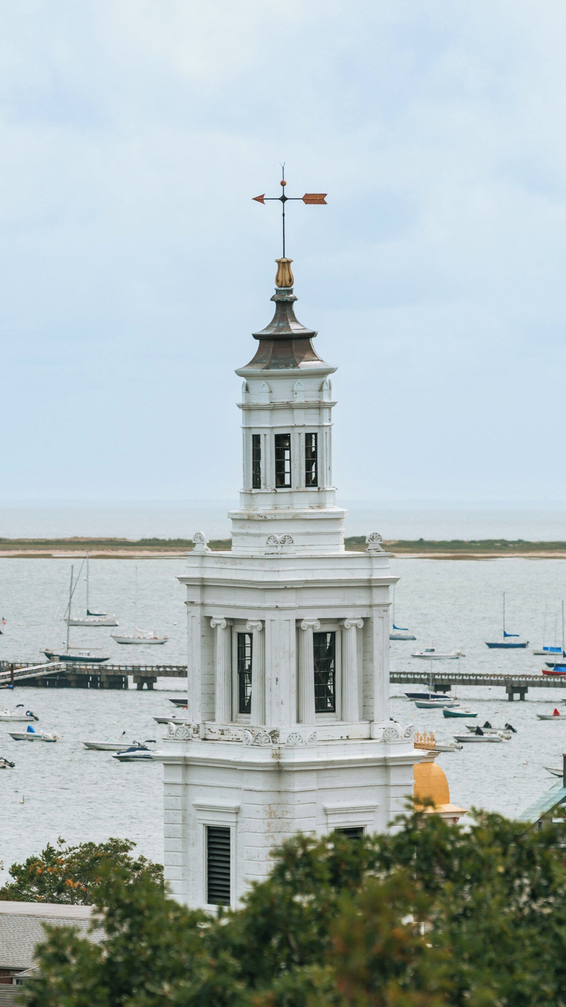 Pilgrim Monument stands tall in Provincetown, Massachusetts, overlooking the harbor and boats at sunset