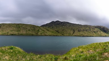 A lake surrounded by green hills and a cloudy sky.