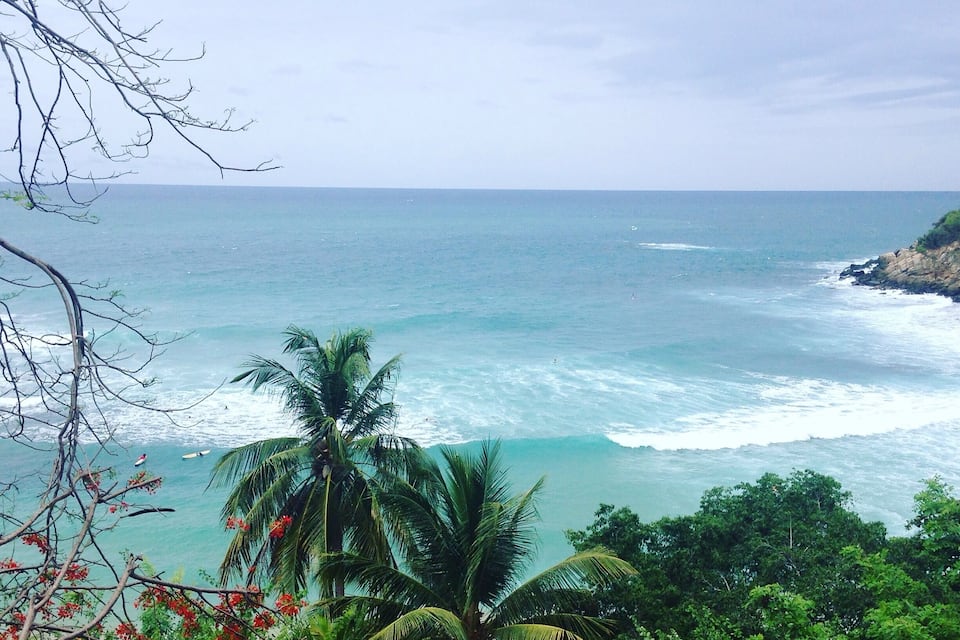 A beach with palm trees and ocean waves.