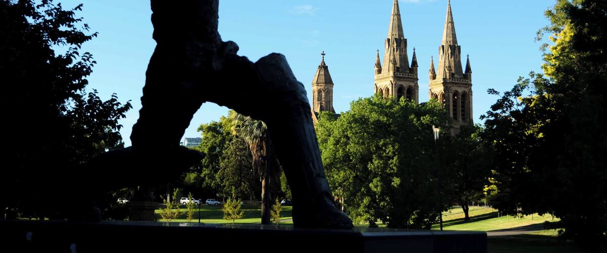Silhouette of Donald Bradman in Pennington Gardens with St. Peter’s Cathedral in the background.