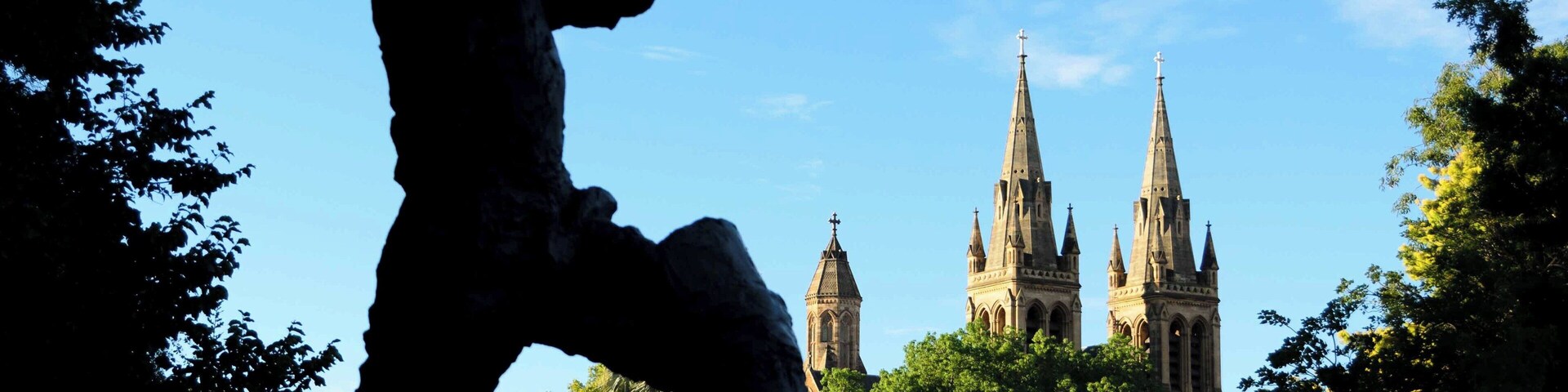 Silhouette of Donald Bradman in Pennington Gardens with St. Peter’s Cathedral in the background.