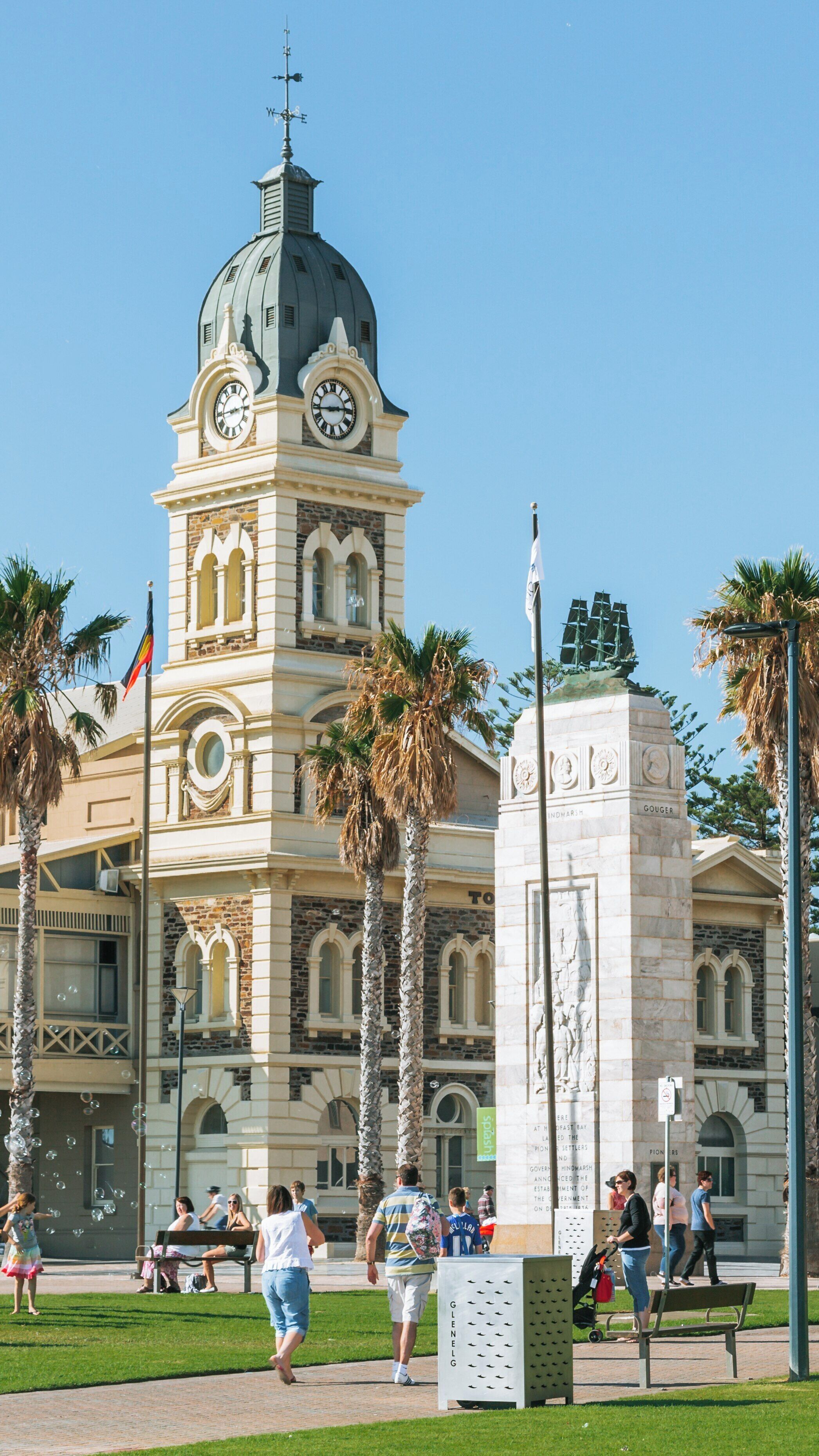 Visitors enjoy a sunny day at Glenelg Beach near the historic Glenelg Town Hall and war memorial in Adelaide, South Australia