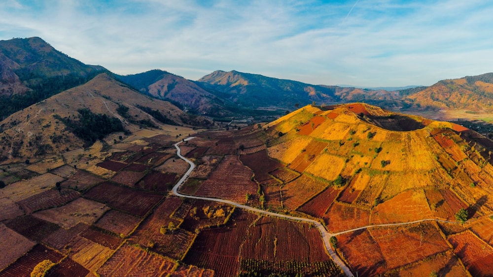 Un paysage montagneux, avec des champs en terrasses et une route sinueuse.