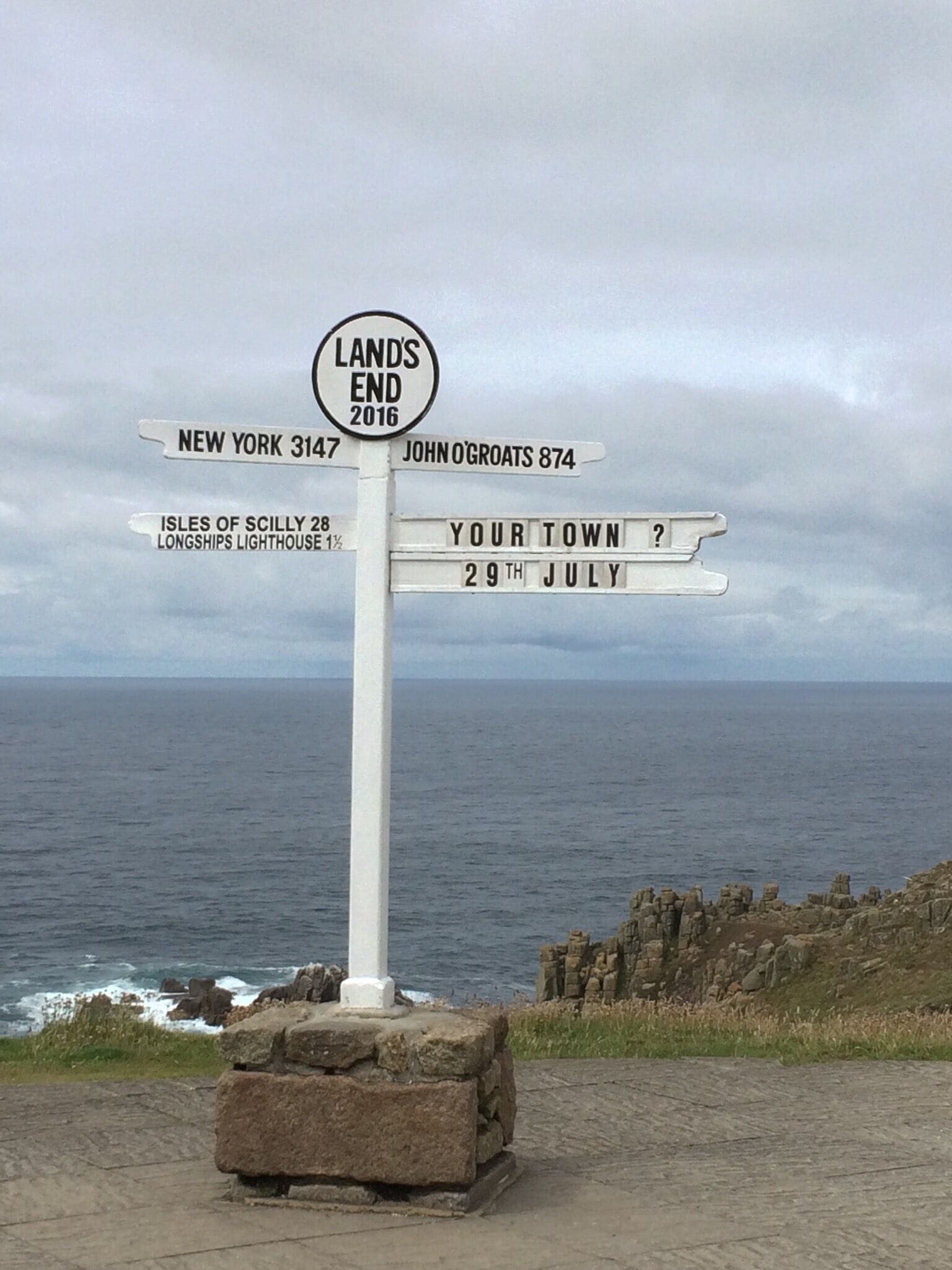 A directional signpost with destinations and a date.