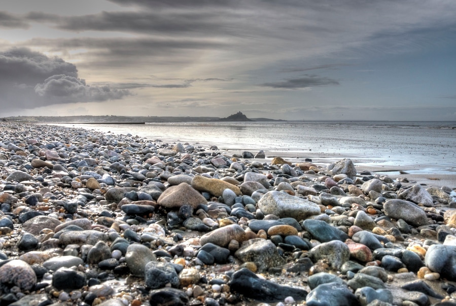 Una playa de guijarros con una isla a lo lejos.