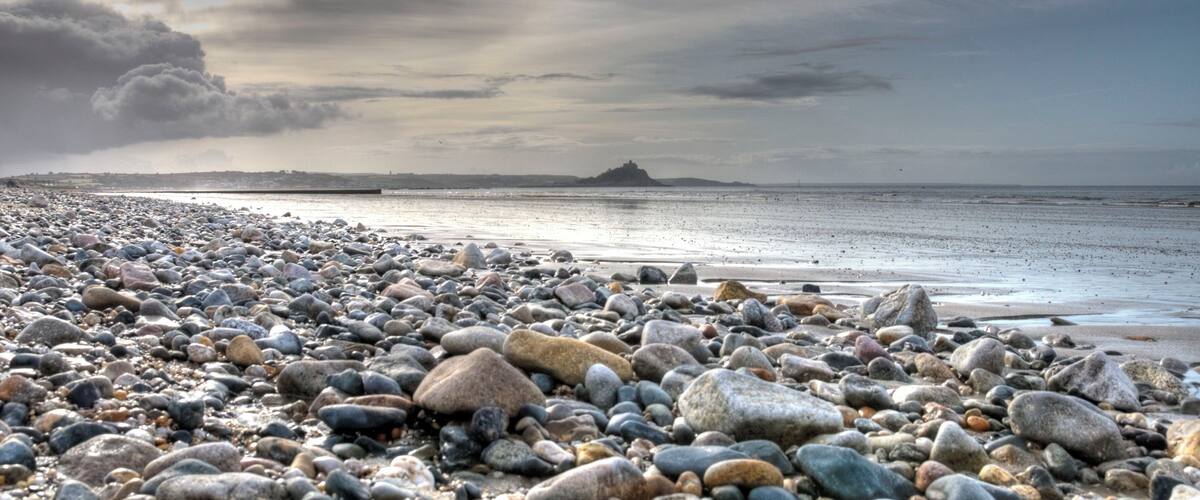 A pebbled beach with a distant island.