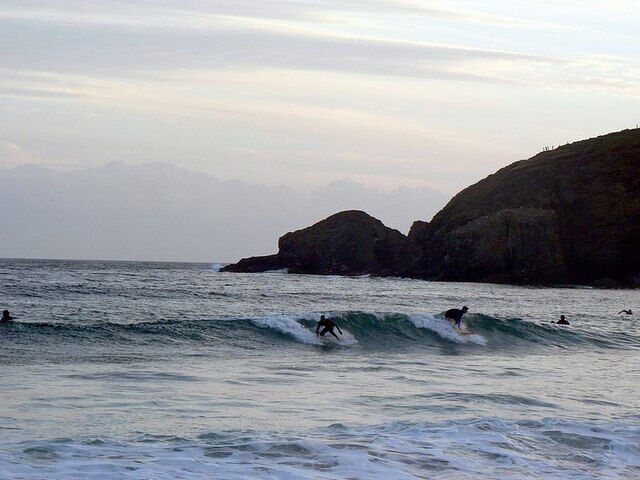 Hoe Point. Seen from the beach near Sydney Cove at Praa Sands. With late evening surfers.