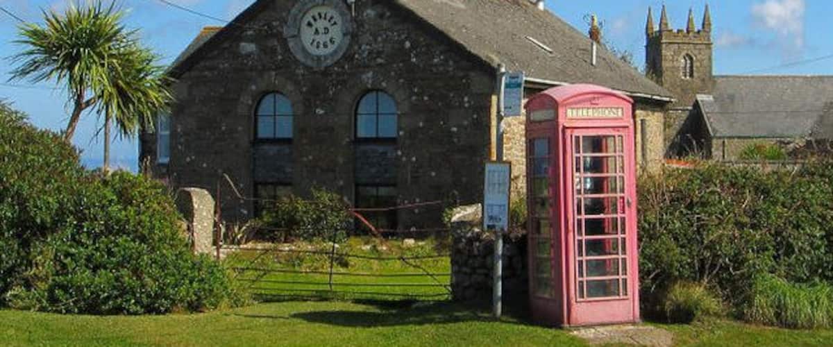 Un edificio de piedra con una cabina telefónica roja e iglesia al fondo.